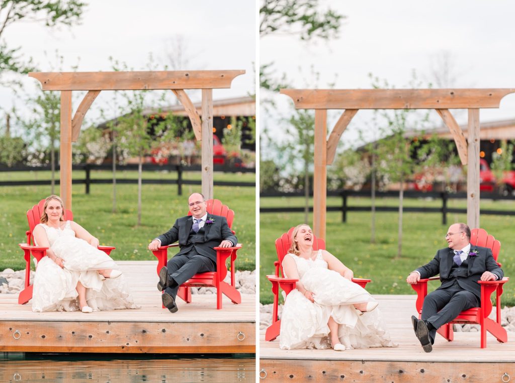 a bride and groom laugh together while sitting on red muskoka chairs