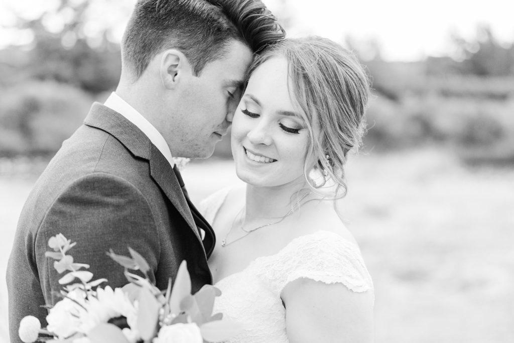 a groom rests his nose on a bride's cheek and they snuggle together